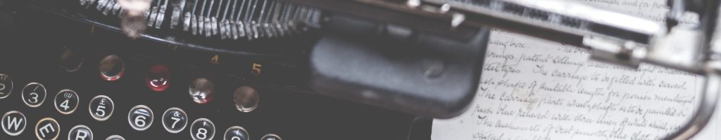 A closeup shot of an old vintage typewriter on a red desk with paper on the side